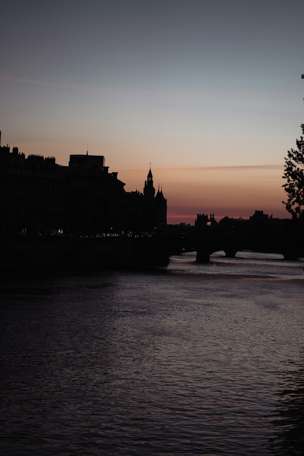 silhouette of building near body of water during sunset