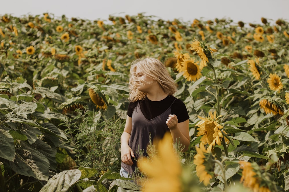 woman in black shirt standing on sunflower field during daytime