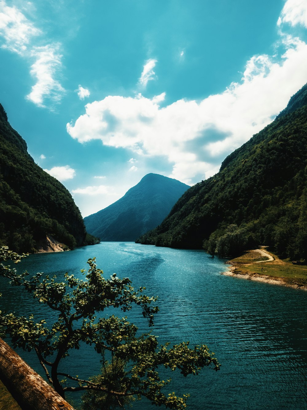 green mountains beside body of water under blue sky during daytime