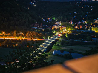 A night shot of a brightly lit train crossing a peaceful river bridge.