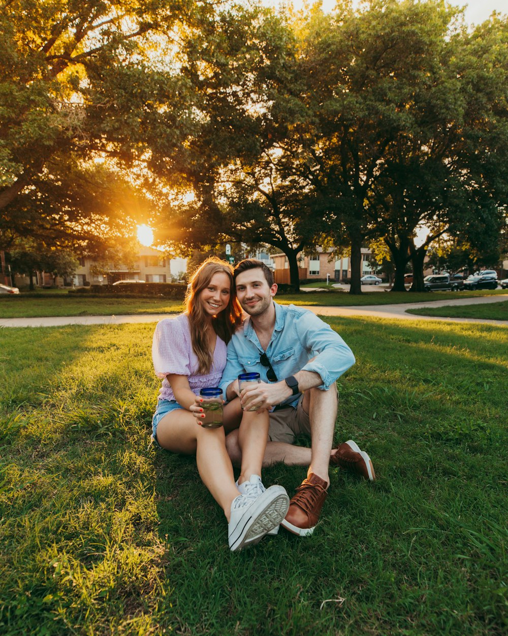 man and woman sitting on green grass field during sunset