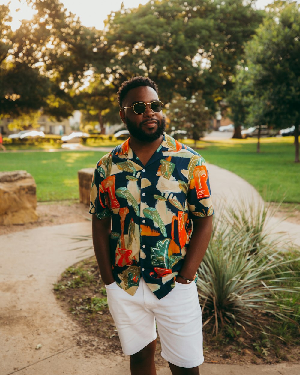 man in yellow green and red floral button up shirt and white pants standing on green