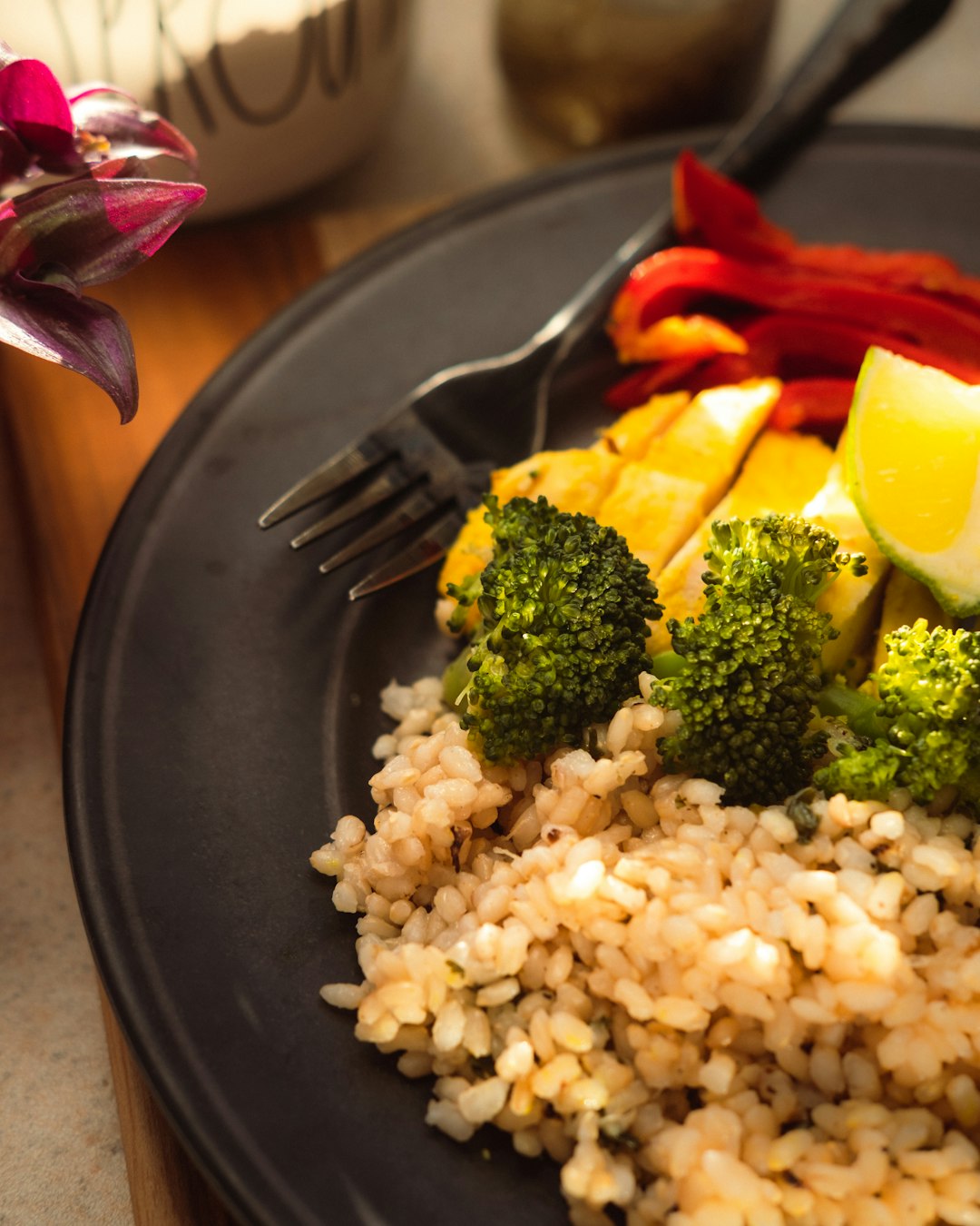 cooked rice with broccoli and carrots on black plate