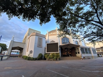 Elegant church exterior decorated with white flowers and green garlands on a sunny day.