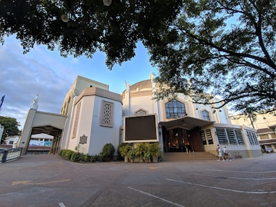 Elegant church exterior decorated with white flowers and green garlands on a sunny day.