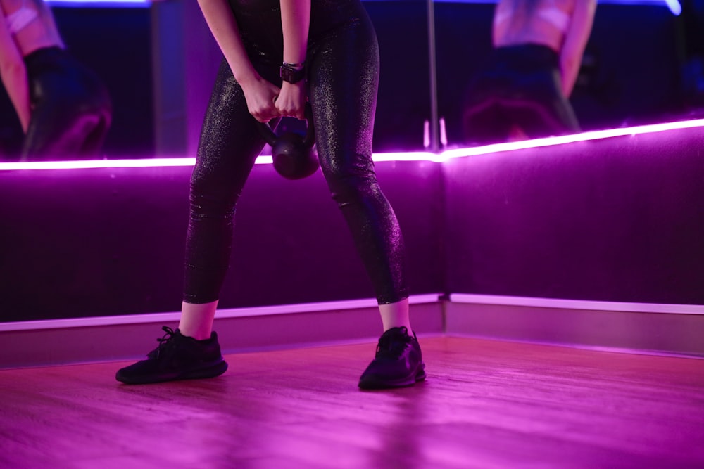 woman in black sports bra and black leggings wearing black leather boots