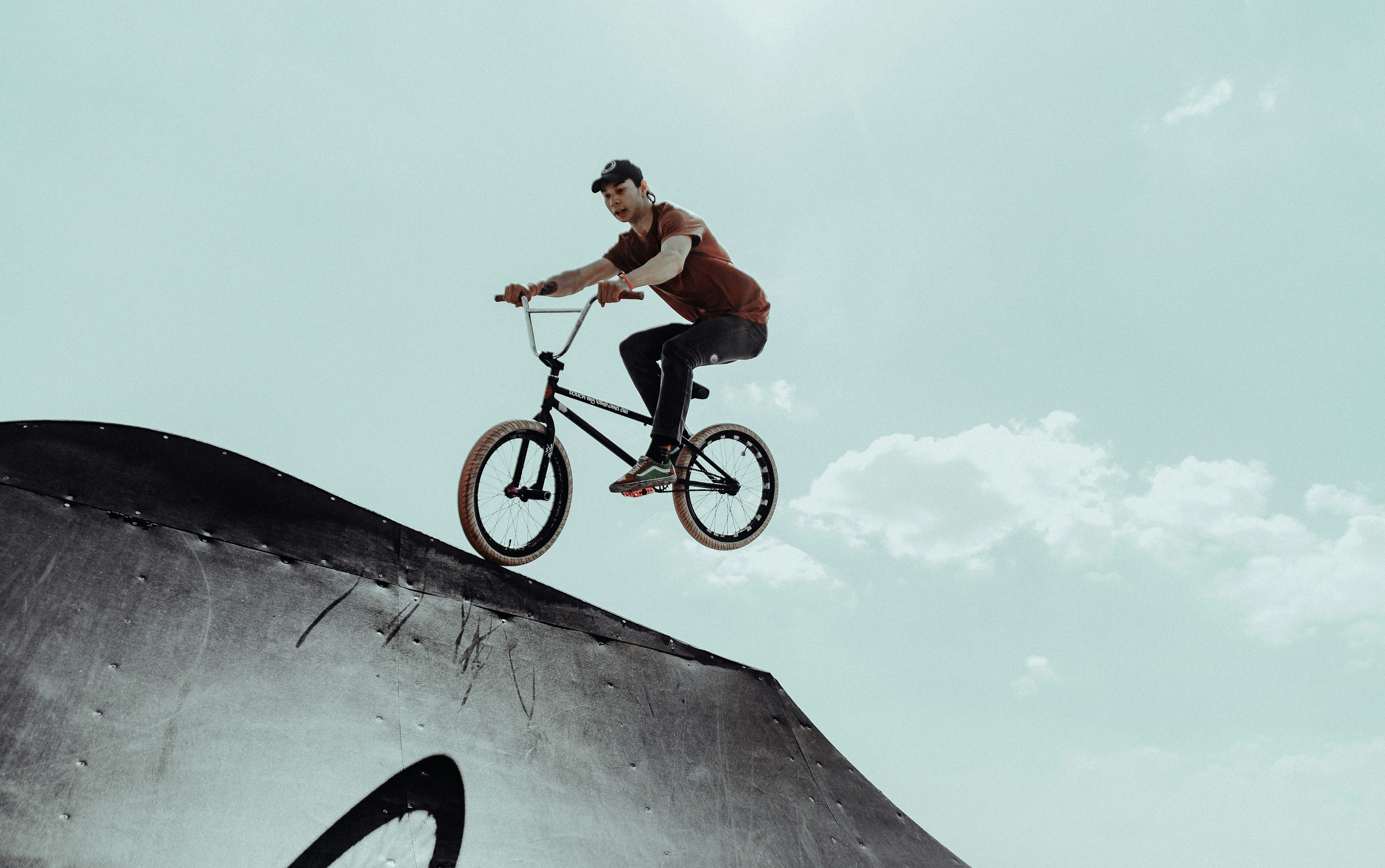 man in orange shirt riding on black bmx bike