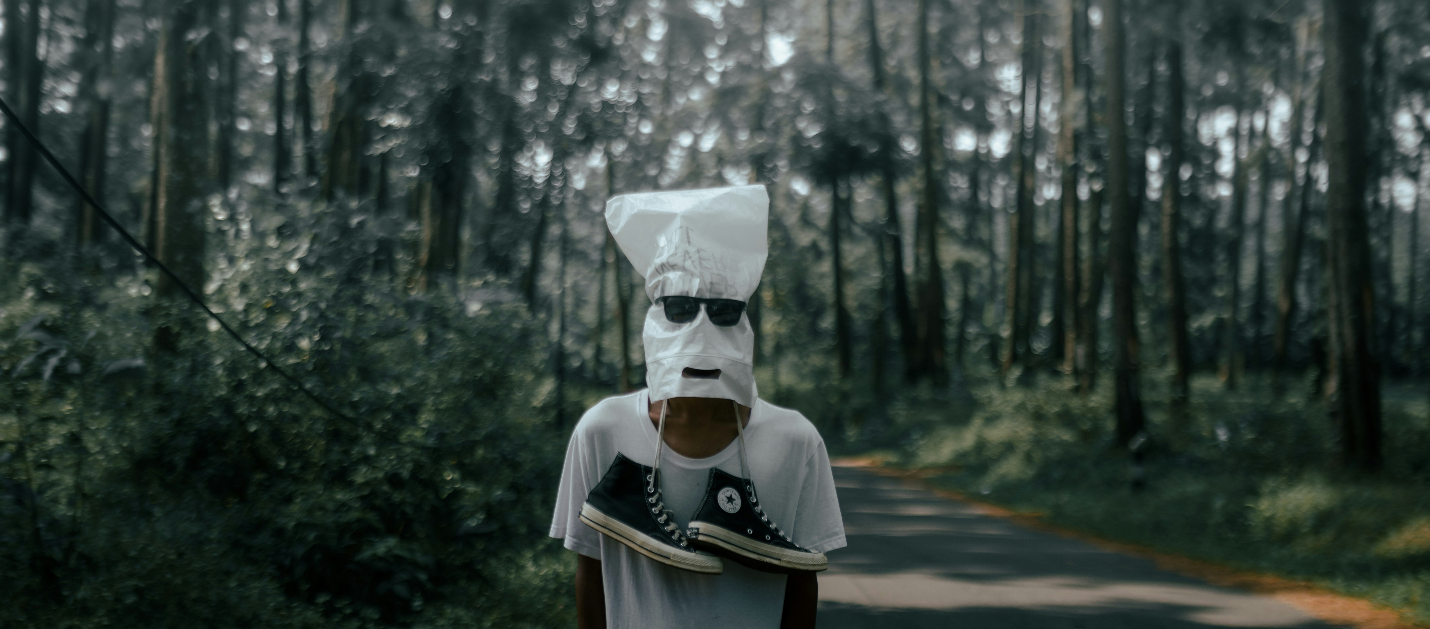 man in white shirt wearing white mask and white mask standing on road during daytime