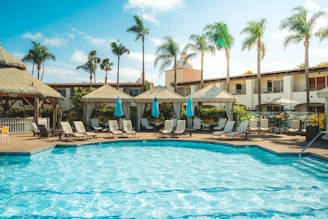 Community pool area with lounge chairs and shaded cabanas.