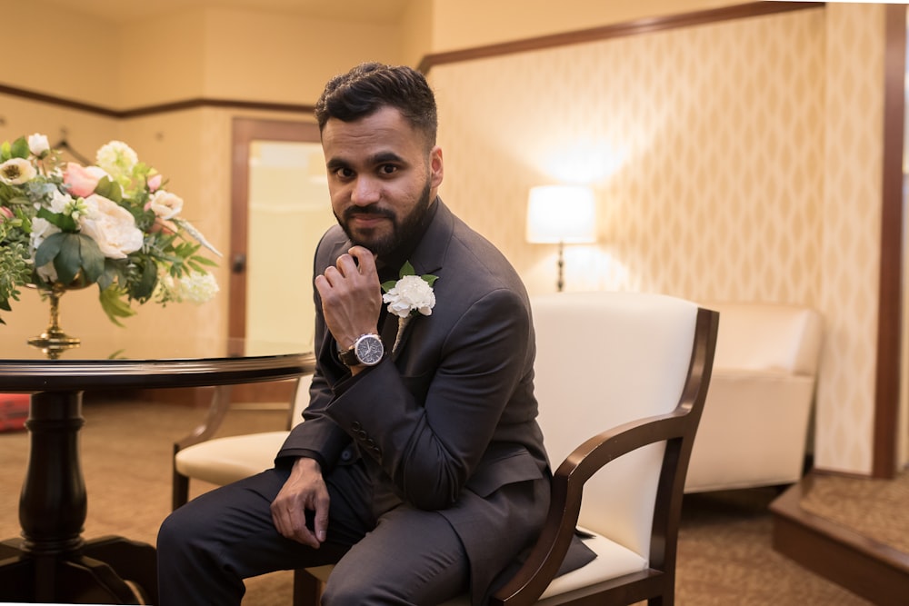 man in black suit sitting on brown wooden armchair