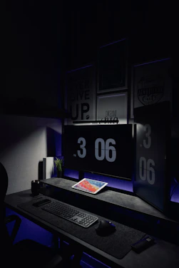 A sleek, minimalist office workspace with dark tones and cybersecurity data overlays on screens.