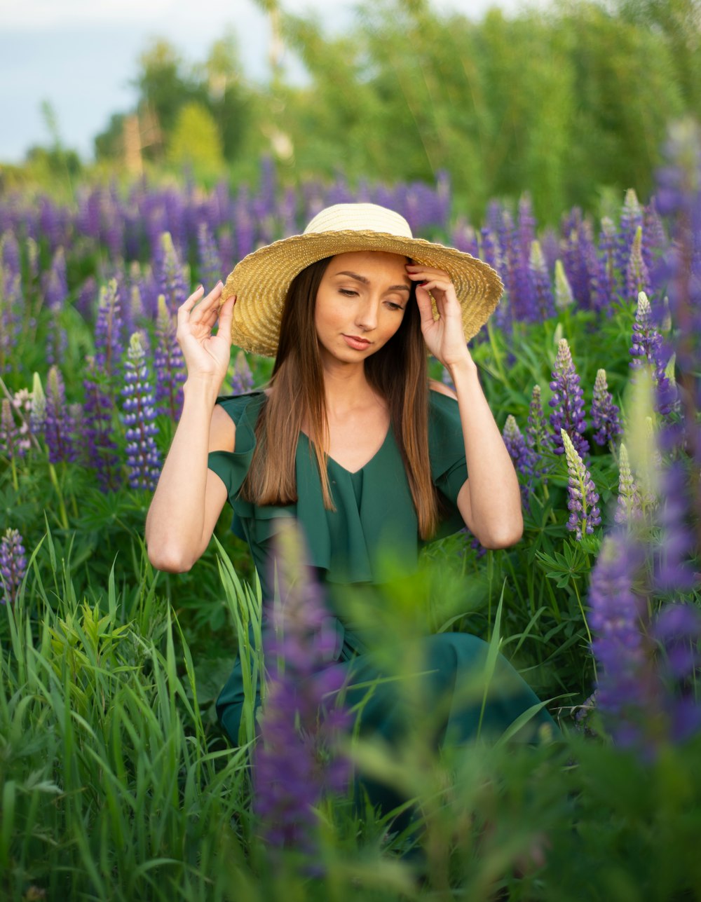 woman in green tank top and brown straw hat standing on purple flower field during daytime