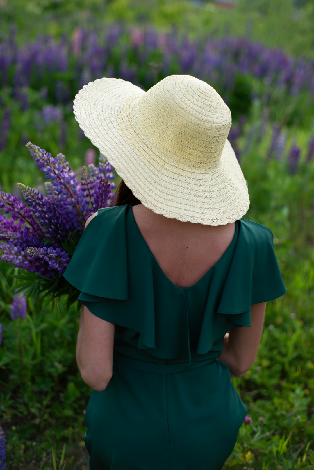 woman in blue dress wearing white knit hat standing on purple flower field during daytime