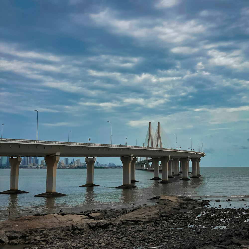 white concrete bridge over the sea under blue sky during daytime