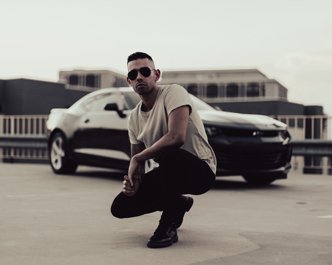 man in white t-shirt and black pants sitting on ground