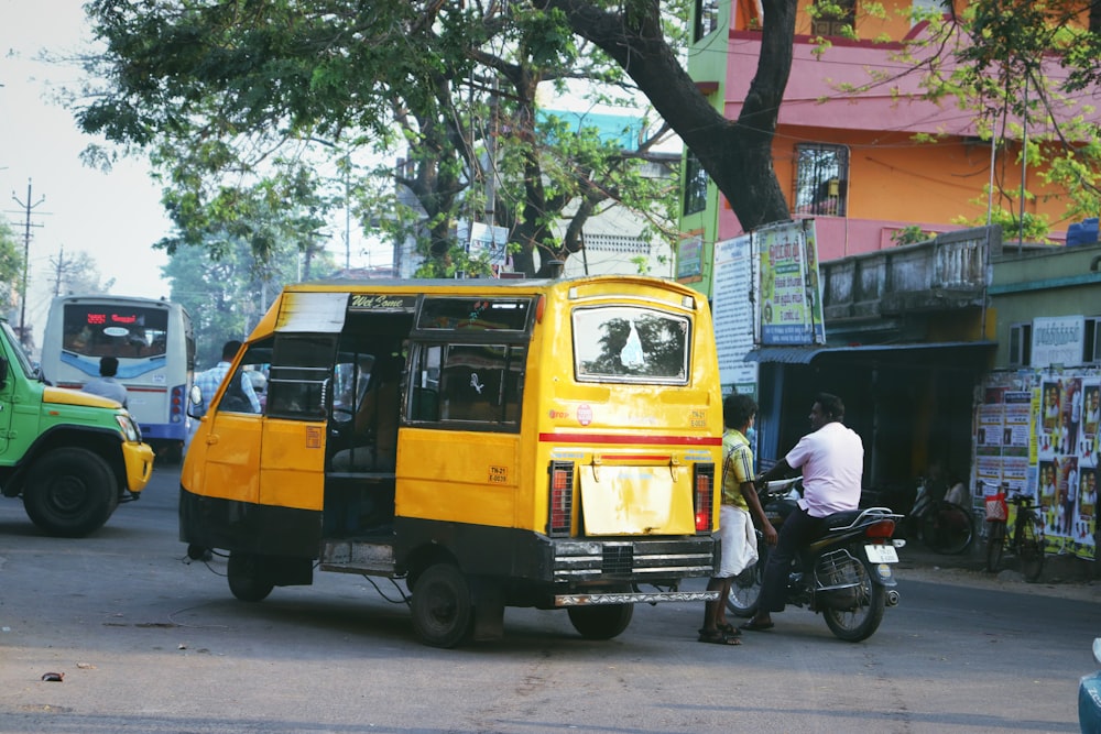 黄色いバスの隣にバイクに乗った男