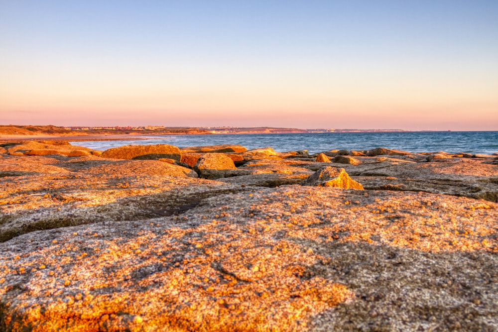 brown sand with rocks under blue sky during daytime