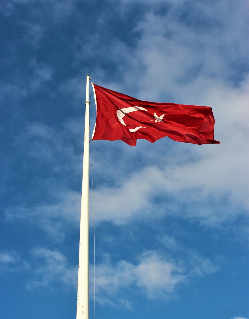 red and white flag on pole under blue sky during daytime