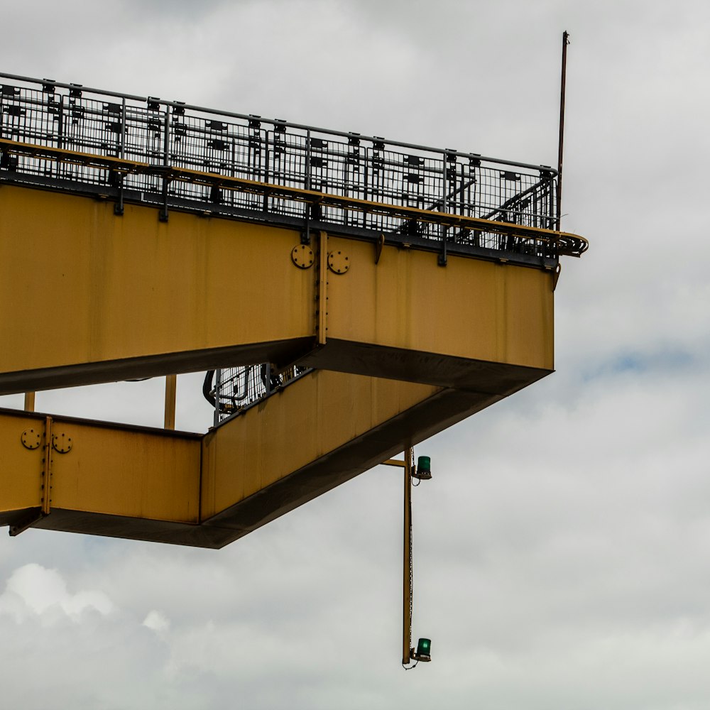 yellow and black metal bridge under cloudy sky