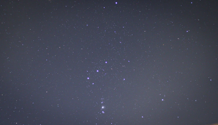 A serene night sky with the Orion constellation shining brightly above a calm landscape, symbolizing guidance and clarity.