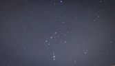 A serene night sky with the Orion constellation shining brightly above a calm landscape, symbolizing guidance and clarity.