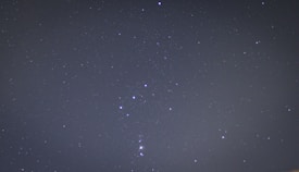 A clear night sky filled with stars. The constellation Orion is prominently visible with its distinct arrangement of bright stars.