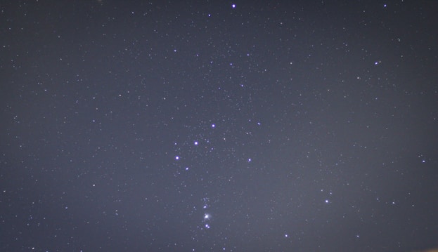 A clear night sky filled with stars. The constellation Orion is prominently visible with its distinct arrangement of bright stars.