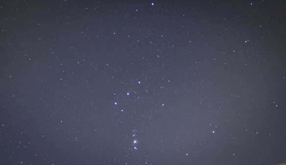 A clear night sky filled with stars. The constellation Orion is prominently visible with its distinct arrangement of bright stars.