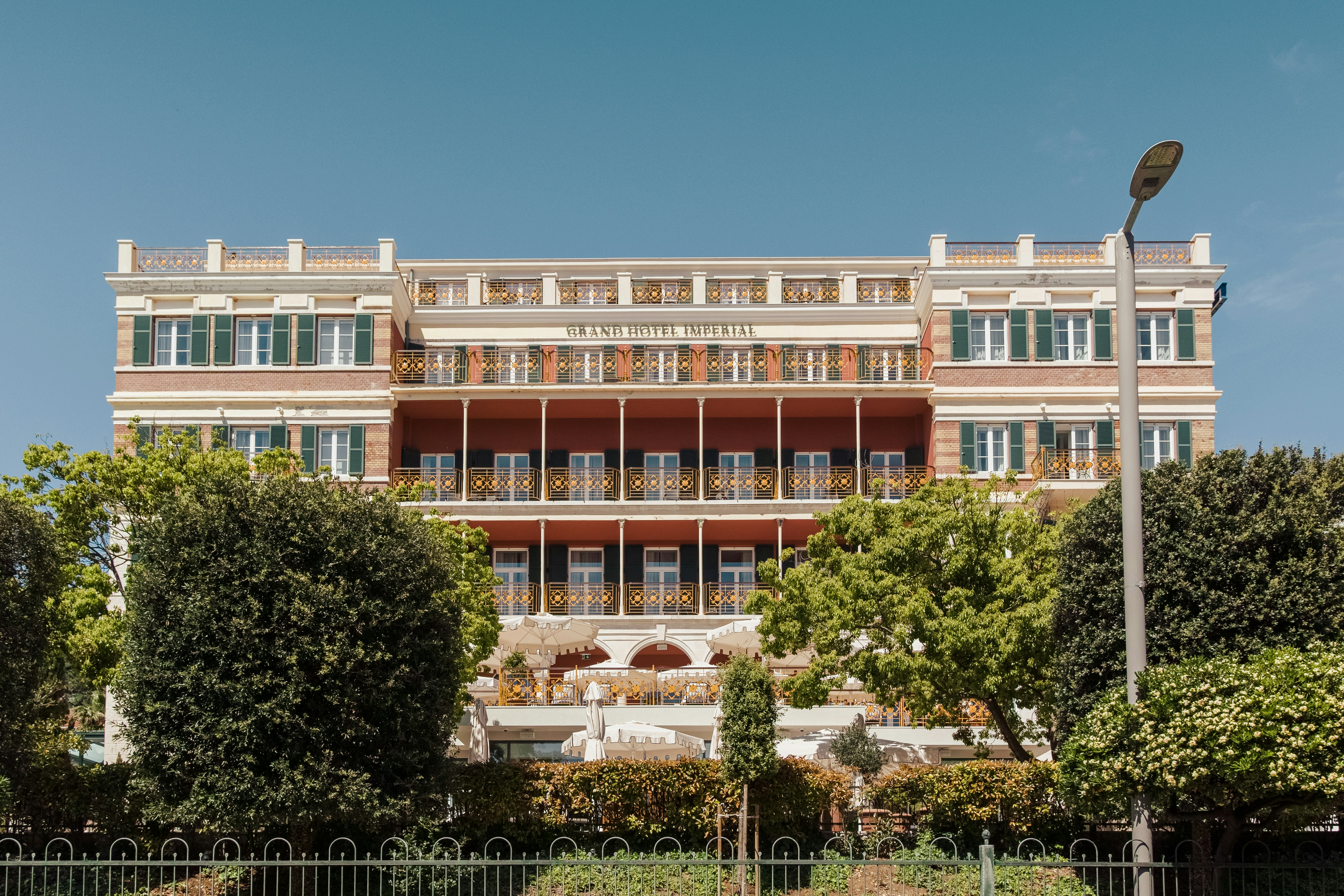 Bâtiment en béton brun près d’arbres verts pendant la journée