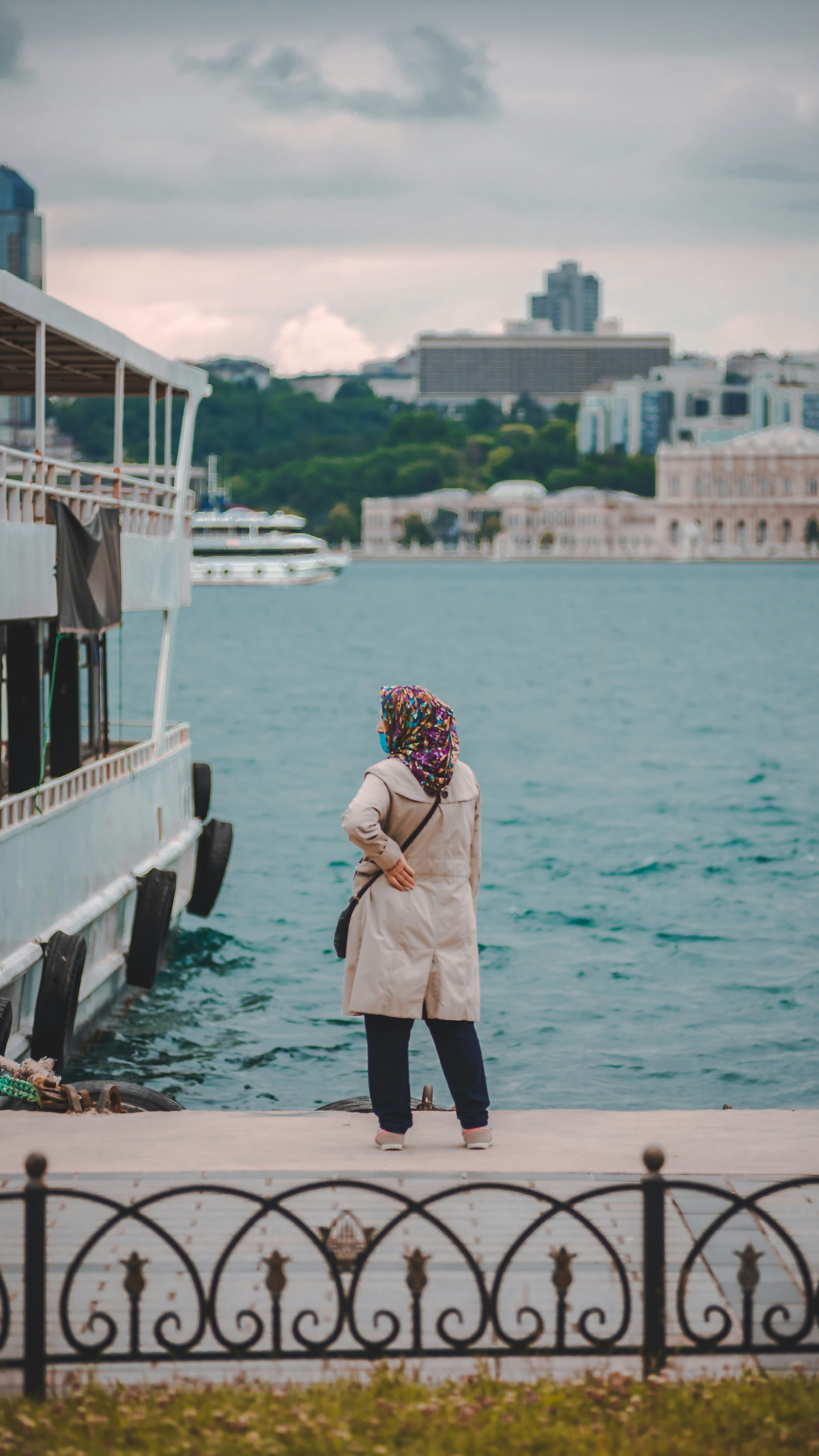 woman in white coat standing on dock during daytime