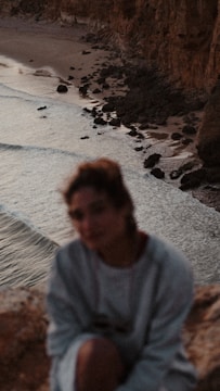 Soft-focus image of a newborn wrapped in a blanket with coastal cliffs in the background