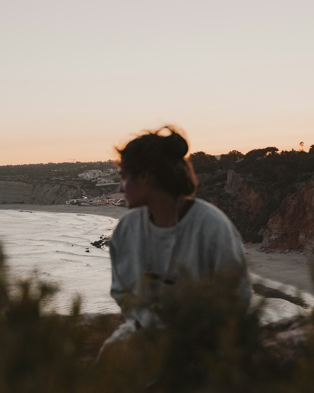 man in white crew neck shirt sitting on rock near body of water during daytime