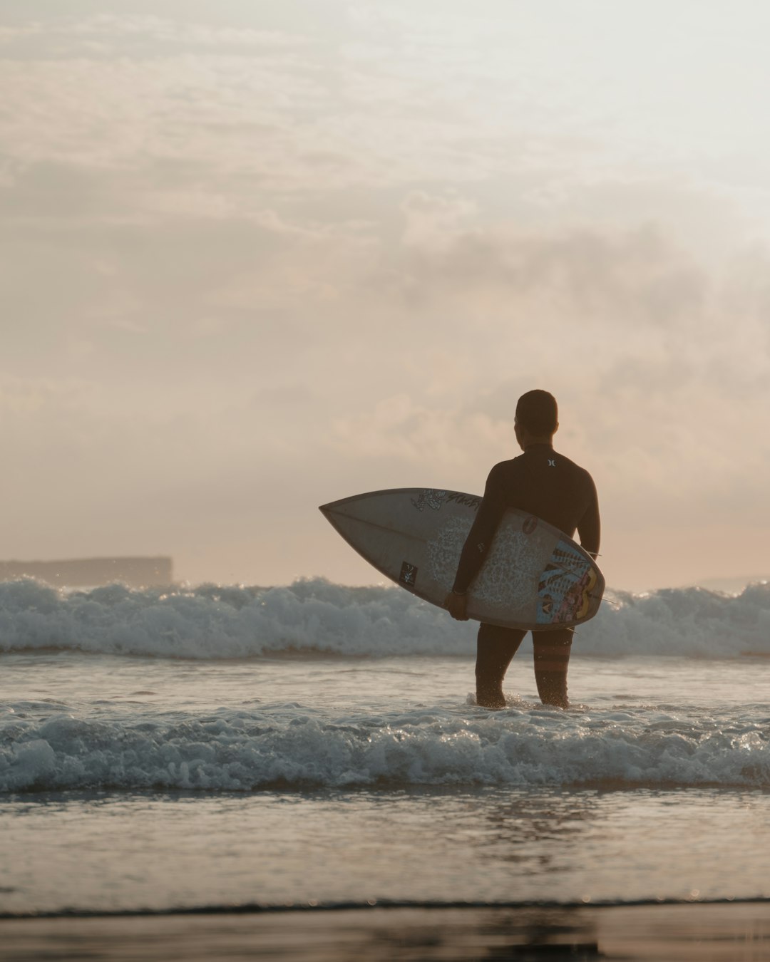 man in white shirt holding white surfboard standing on seashore during daytime