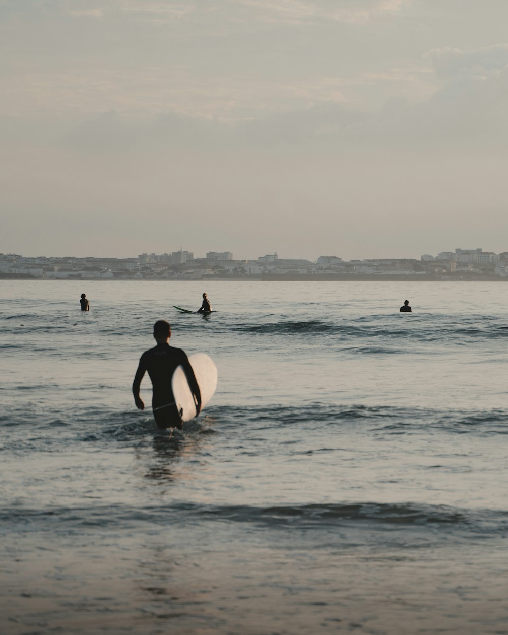man and woman in black wetsuit holding white surfboard on sea during daytime