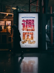 man in black jacket standing near white and red poster