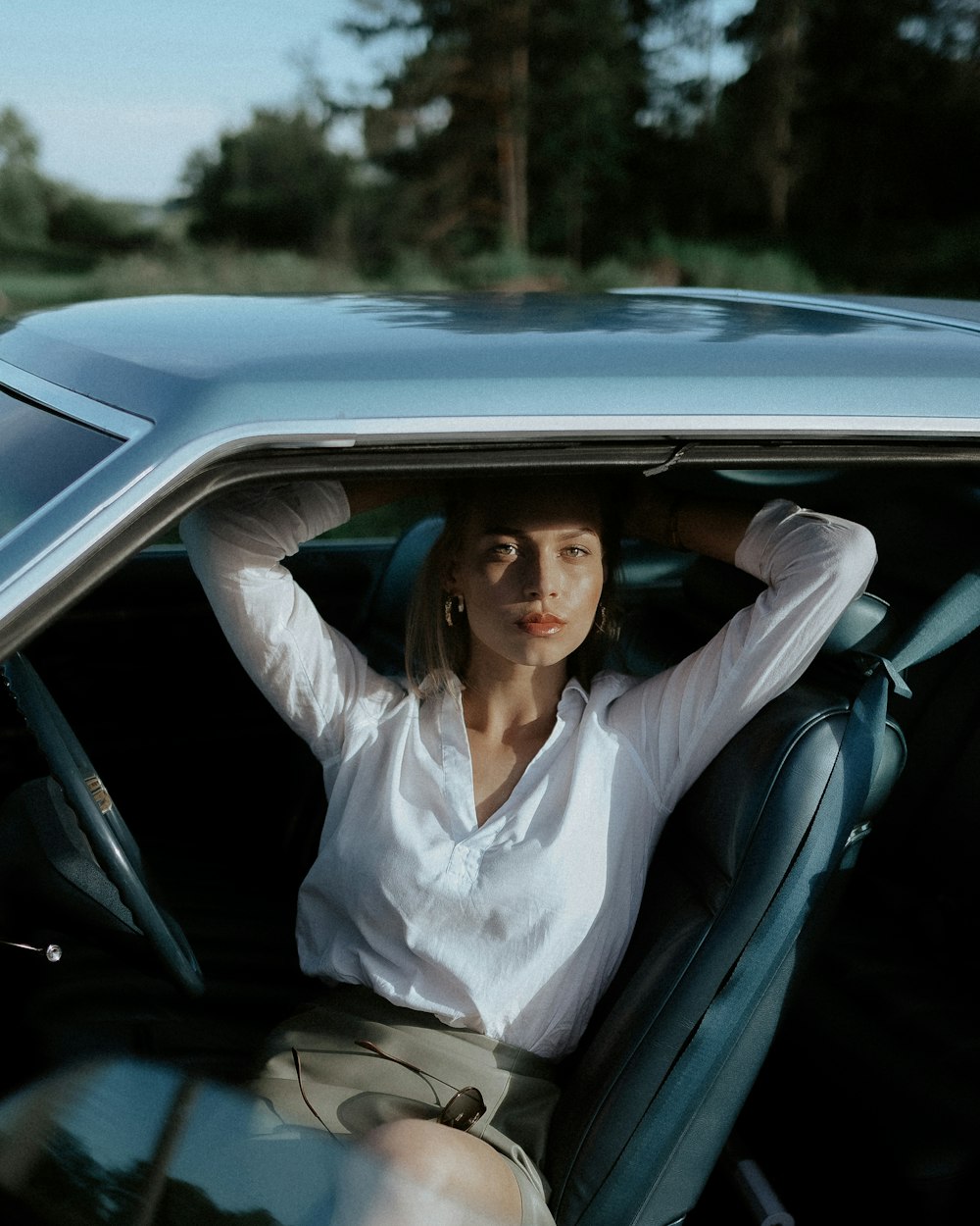 Mujer en camisa de vestir blanca sentada en el asiento del automóvil