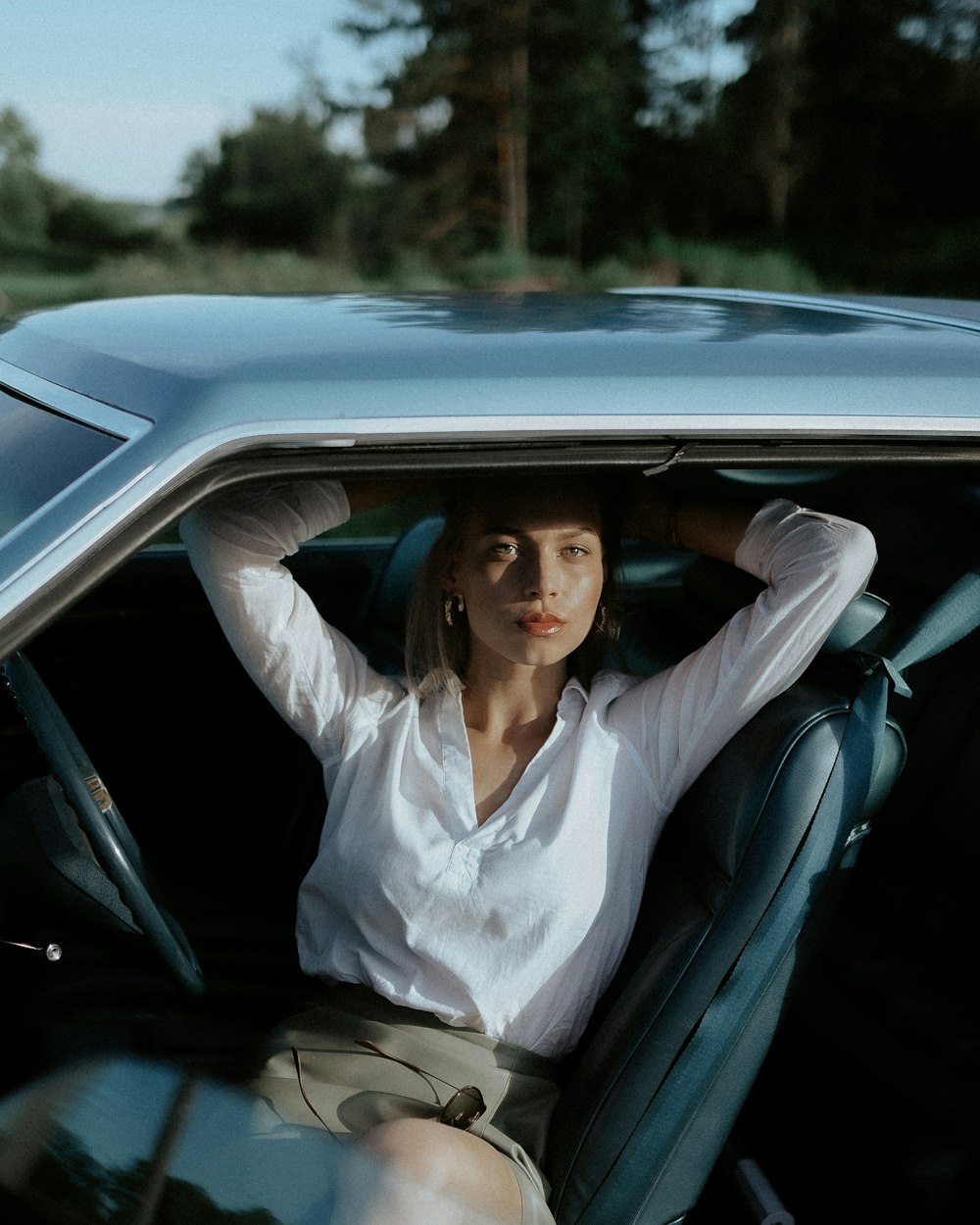 mulher na camisa social branca sentada no assento do carro