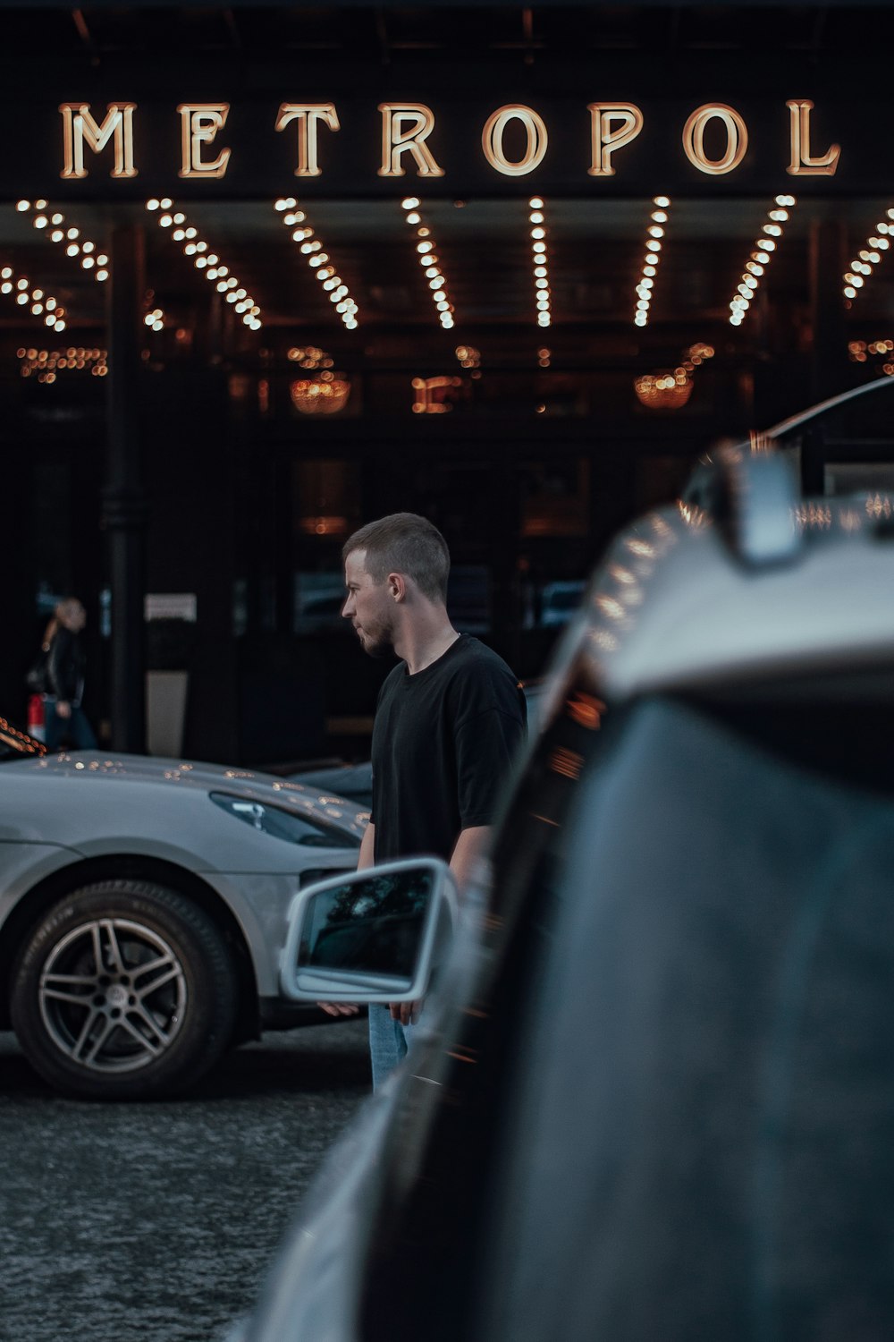 man in black jacket standing beside car during night time