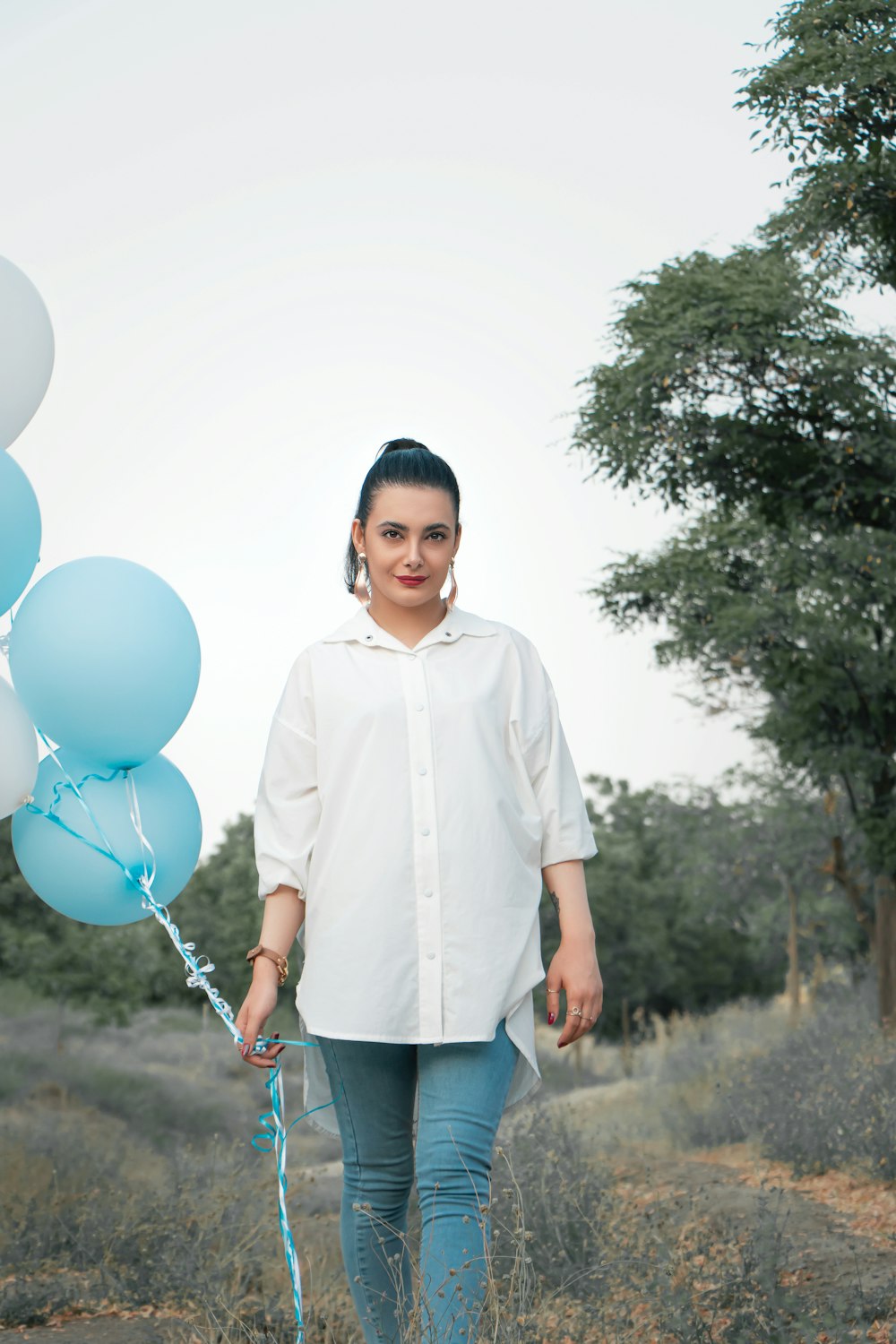 chico con camisa de vestir blanca sosteniendo globos azules