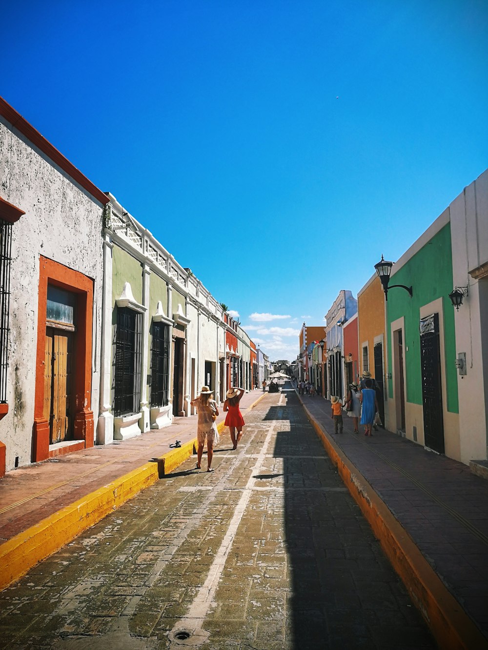 people walking on sidewalk near houses during daytime