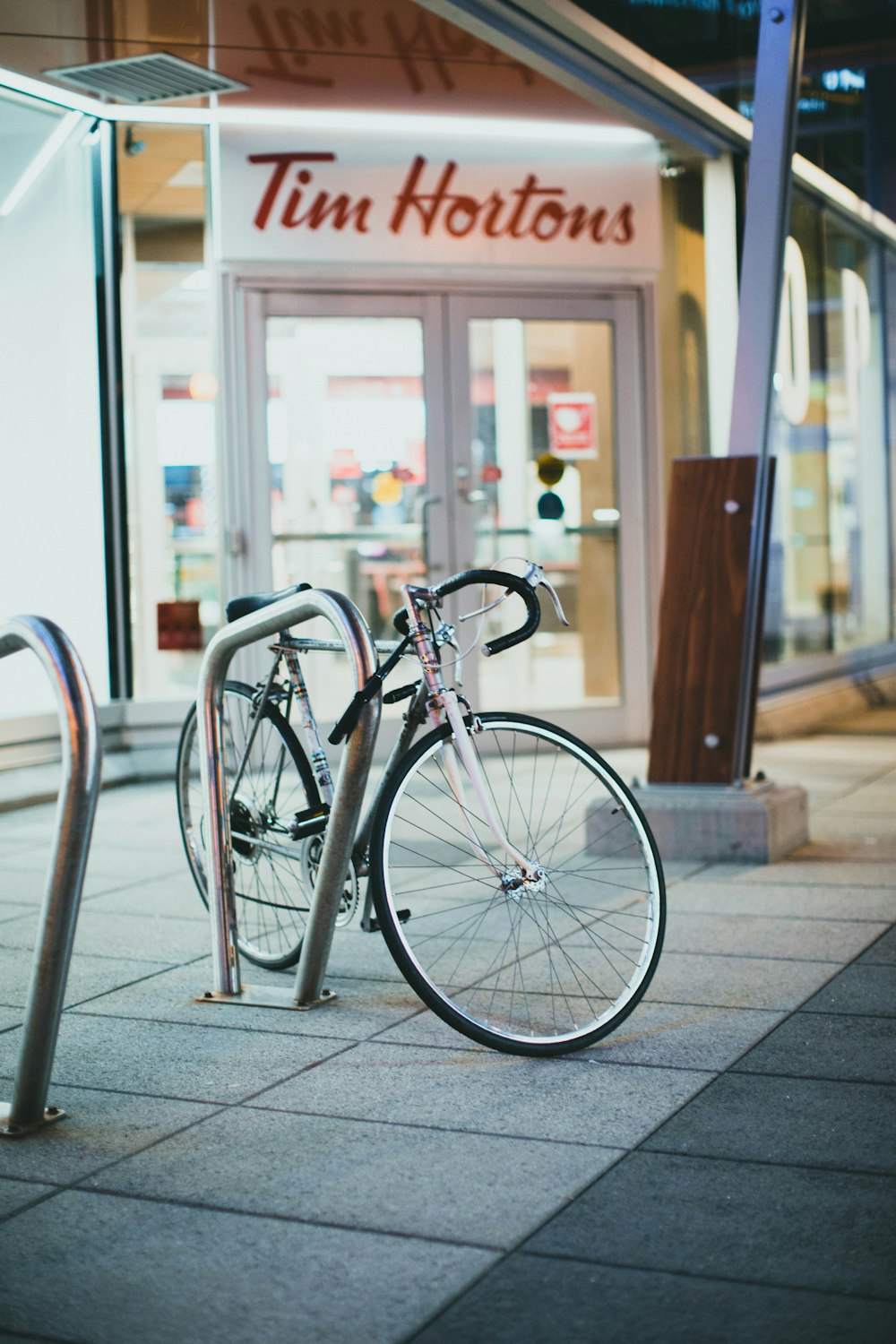 Bicicleta urbana blanca estacionada junto a barandillas de metal blanco durante el día