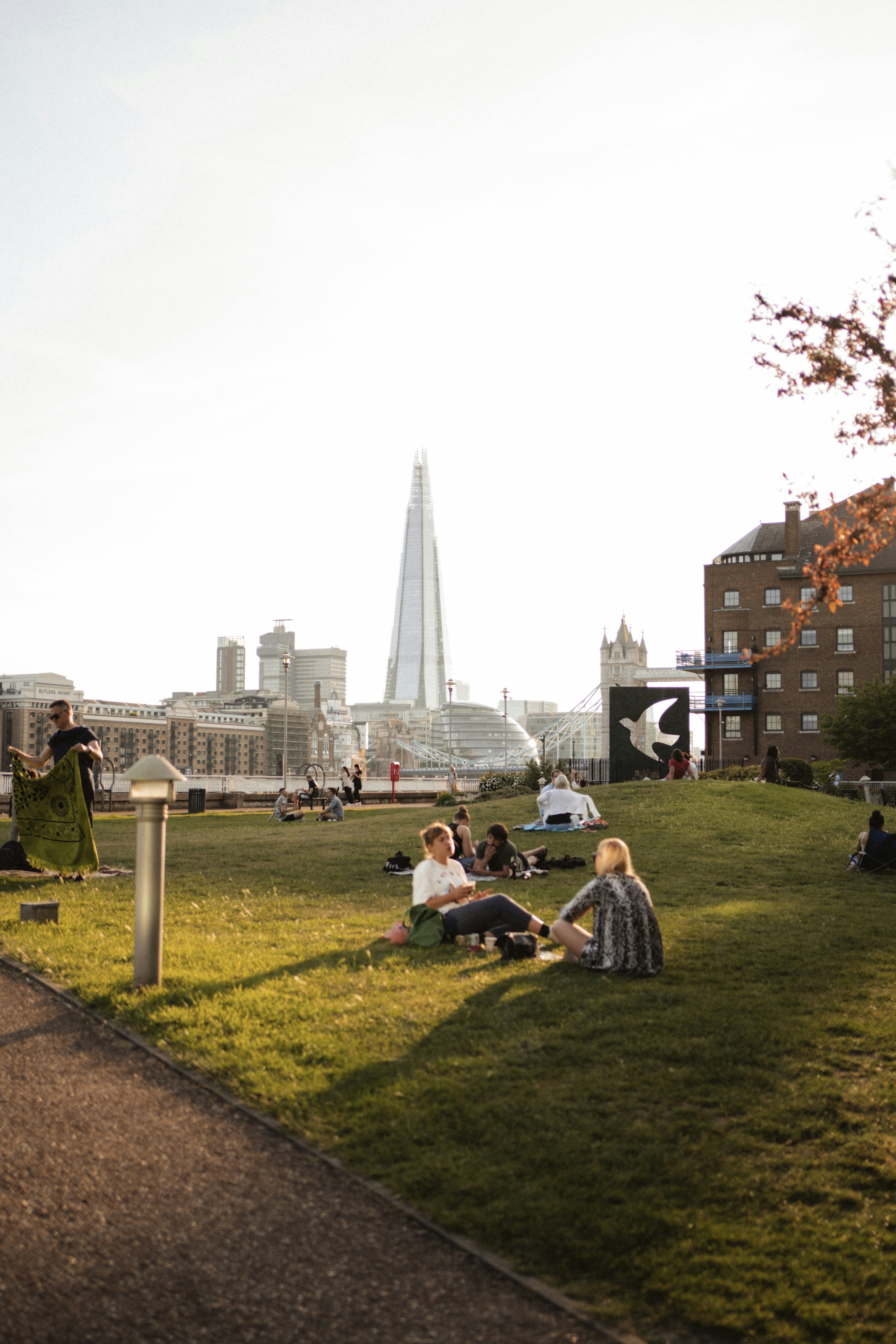 people sitting on green grass field near city buildings during daytime