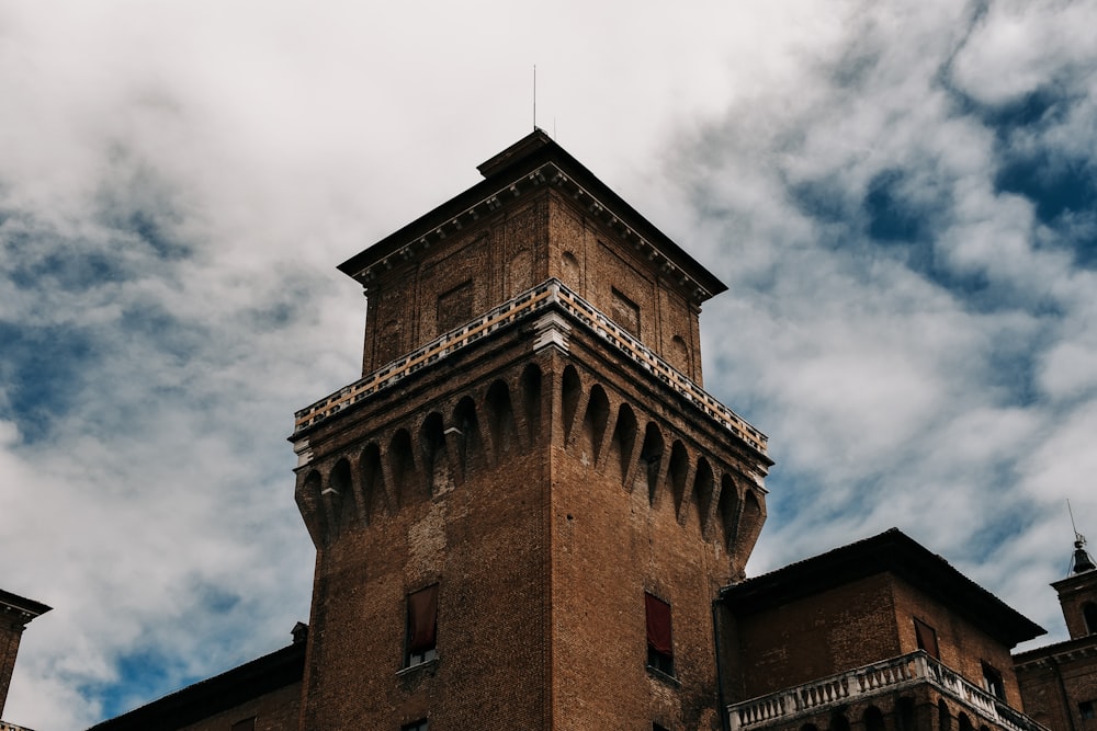 edificio in cemento marrone sotto il cielo nuvoloso durante il giorno