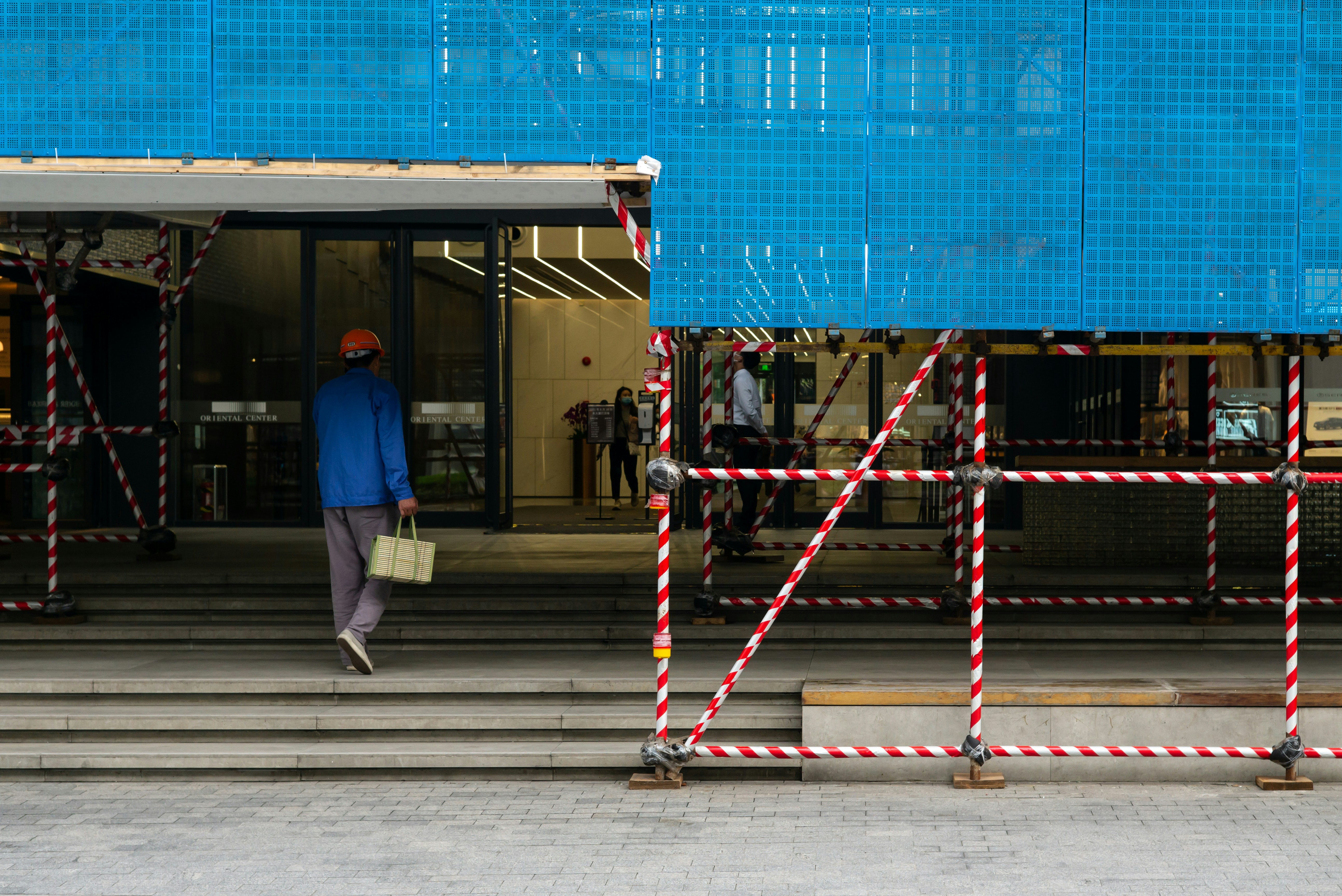 man in blue jacket and gray pants standing on gray concrete floor during daytime