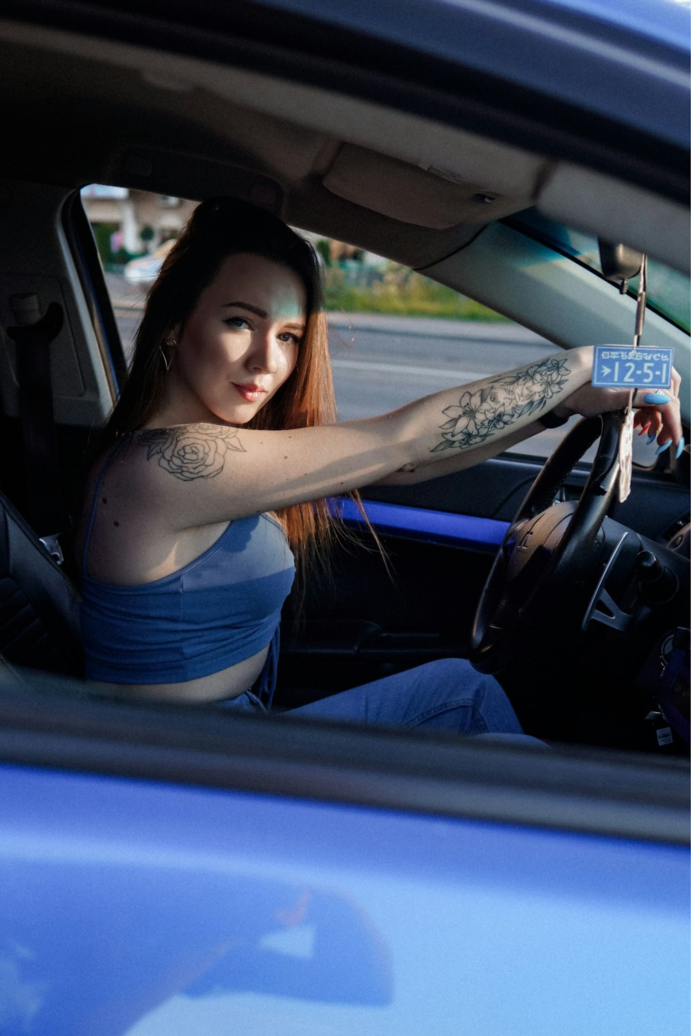 woman in blue tank top and blue denim jeans sitting on car seat
