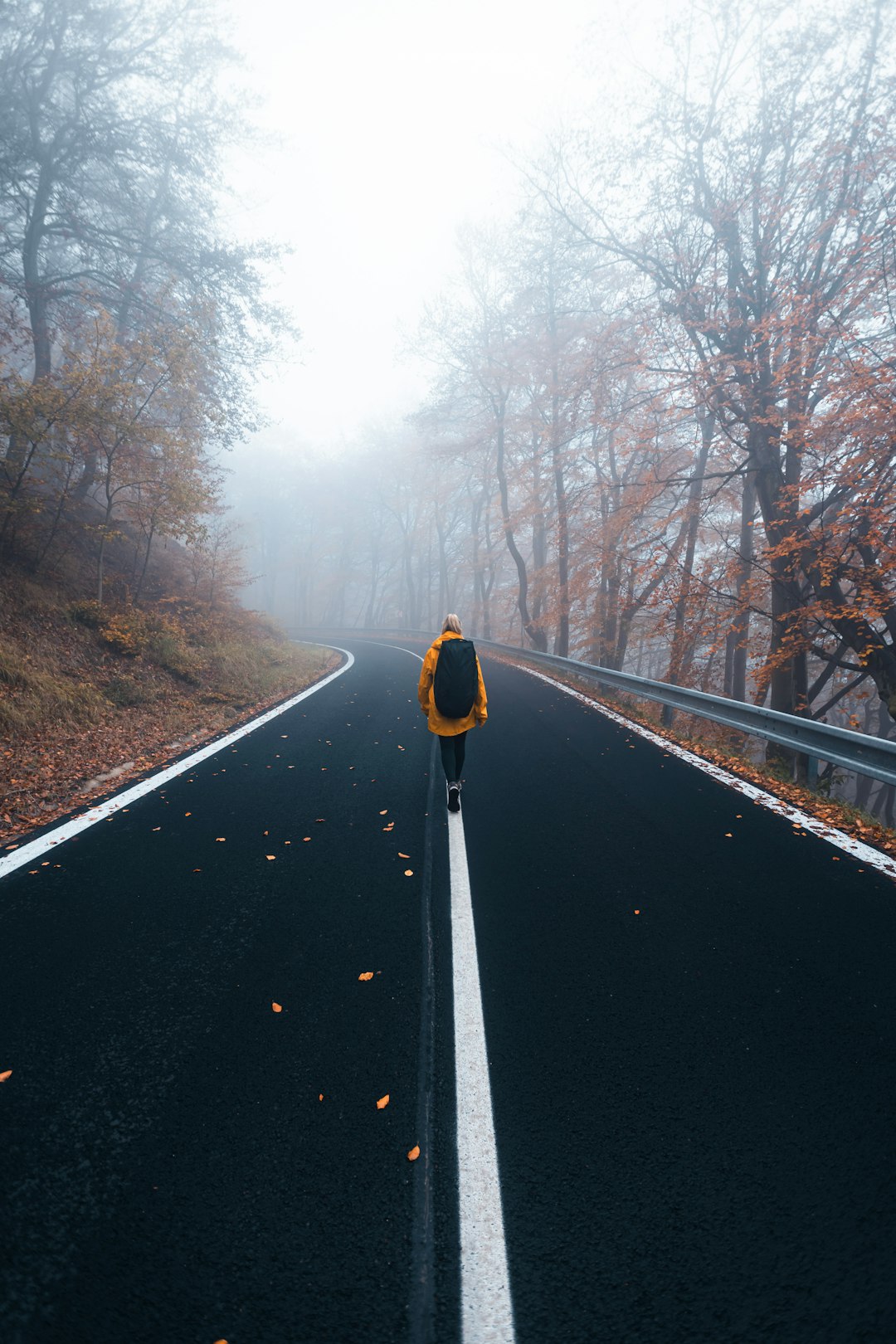 man in yellow jacket and black pants standing on road during daytime