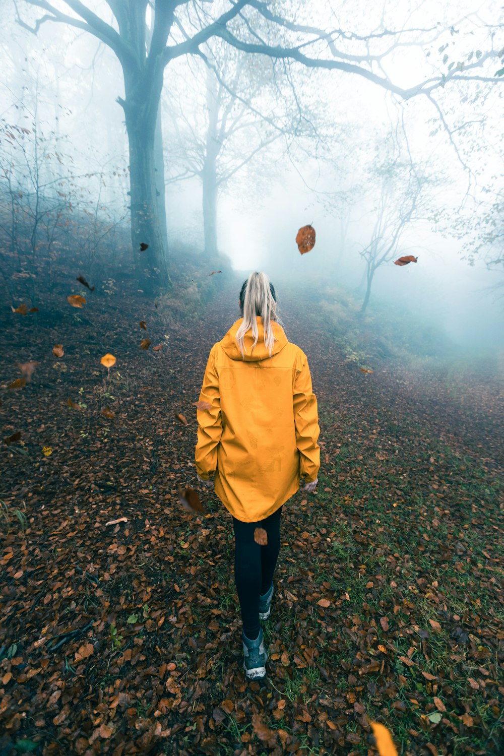 a person in a yellow jacket walking through a forest
