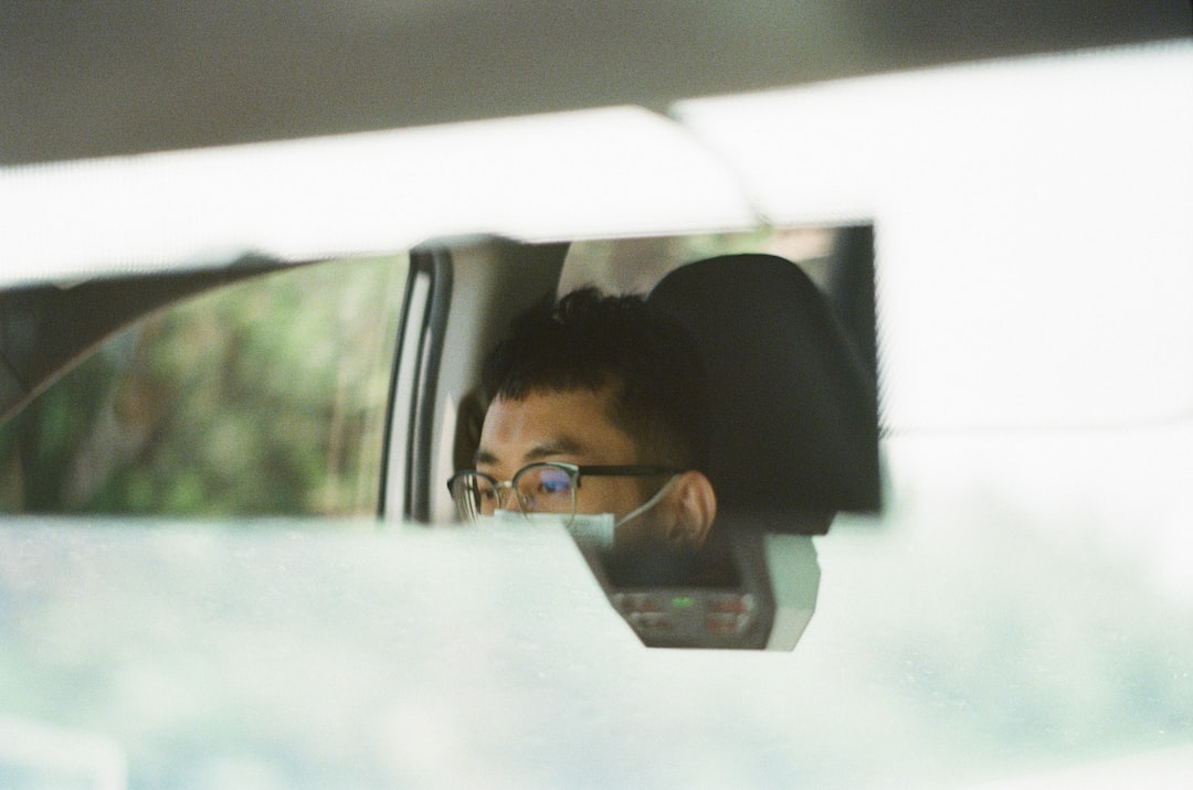 man in black framed eyeglasses driving car