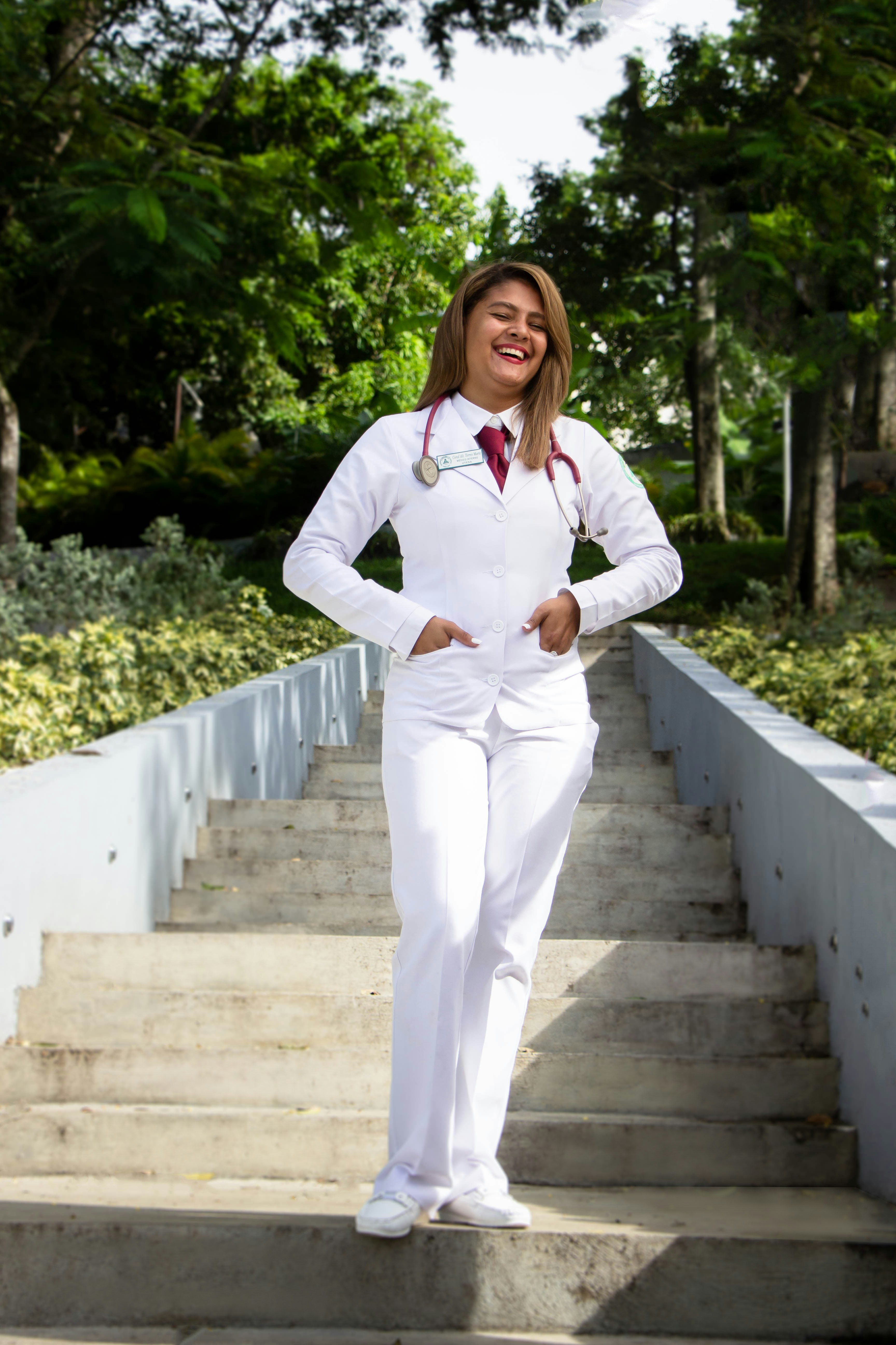 woman in white long sleeve shirt and white pants standing on gray concrete stairs