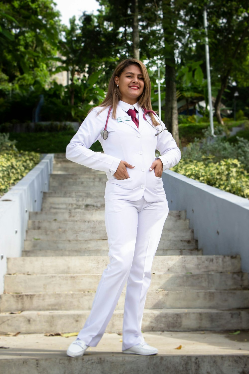 woman in white blazer and white pants standing on concrete stairs